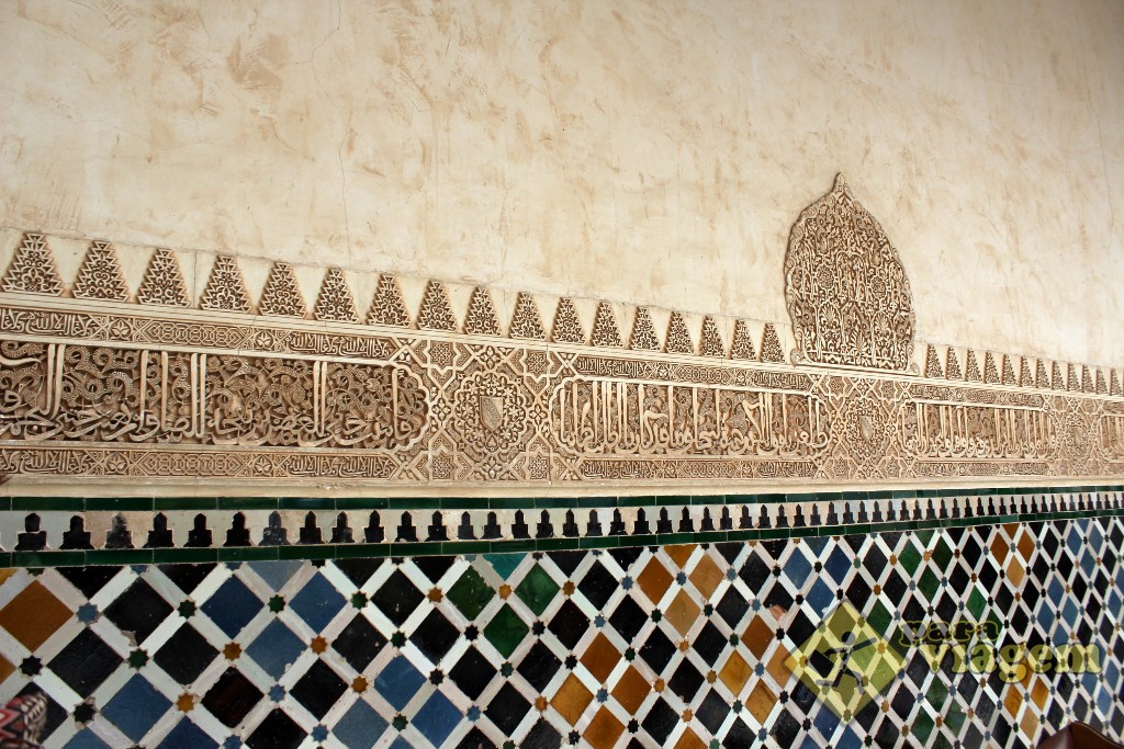Paredes com friso em árabe entre azulejos e arabescos