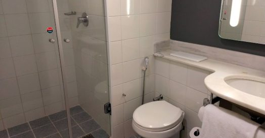 Banheiro com chuveiro no teto e espelho iluminado